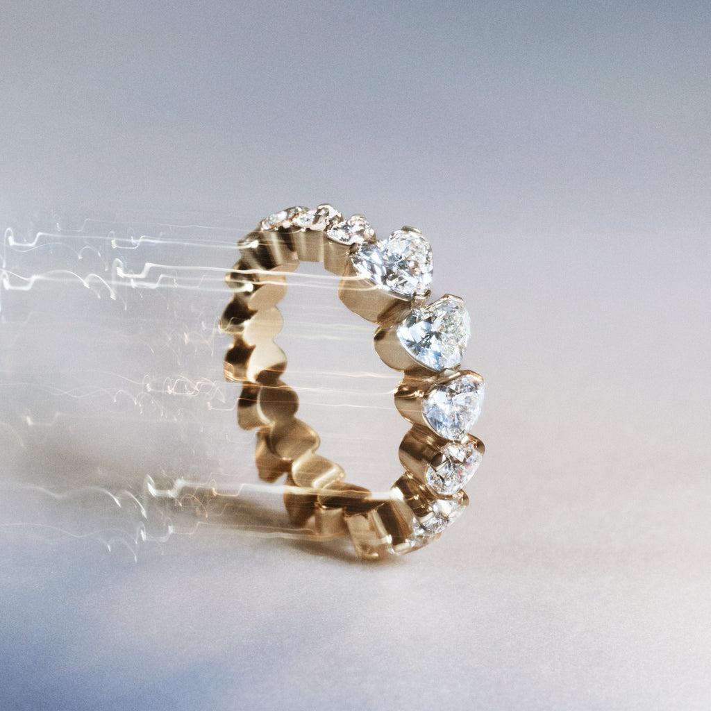 The Ensemble Baronesse diamond ring with graduating heart-shaped diamonds displayed as a still life image on a light grey background.