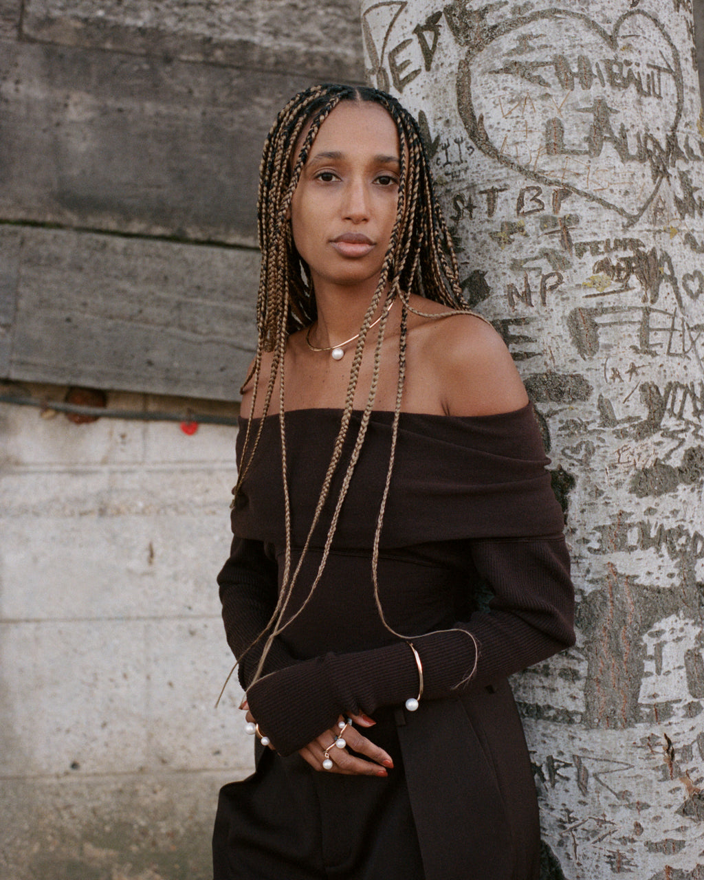 Model wearing a yellow gold choker with a large center pearl, a yellow gold bangle with a large pearl and three pearl rings.