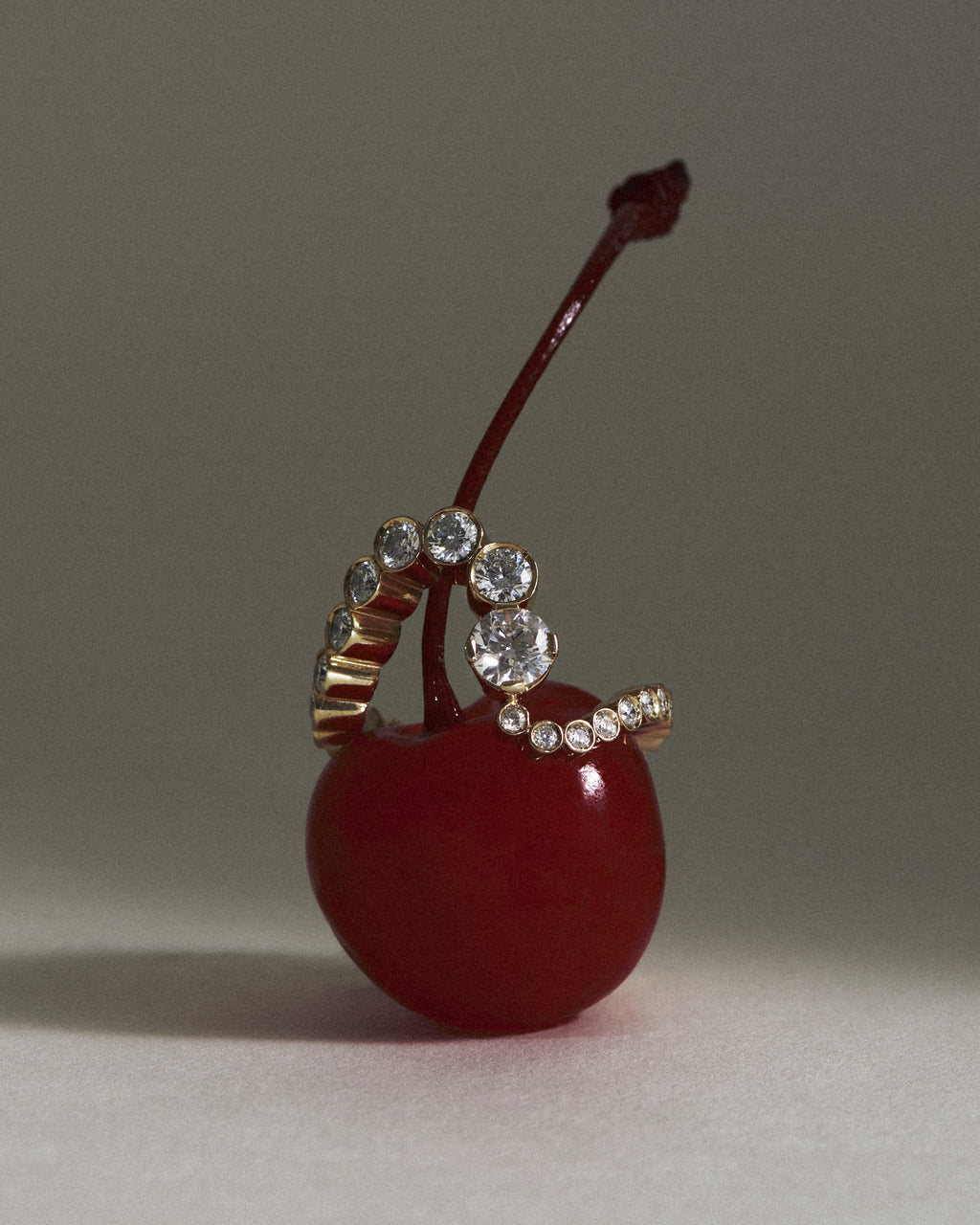 The Grand Ensemble Ocean 18K yellow gold diamond ring is placed on top of a red cherry.