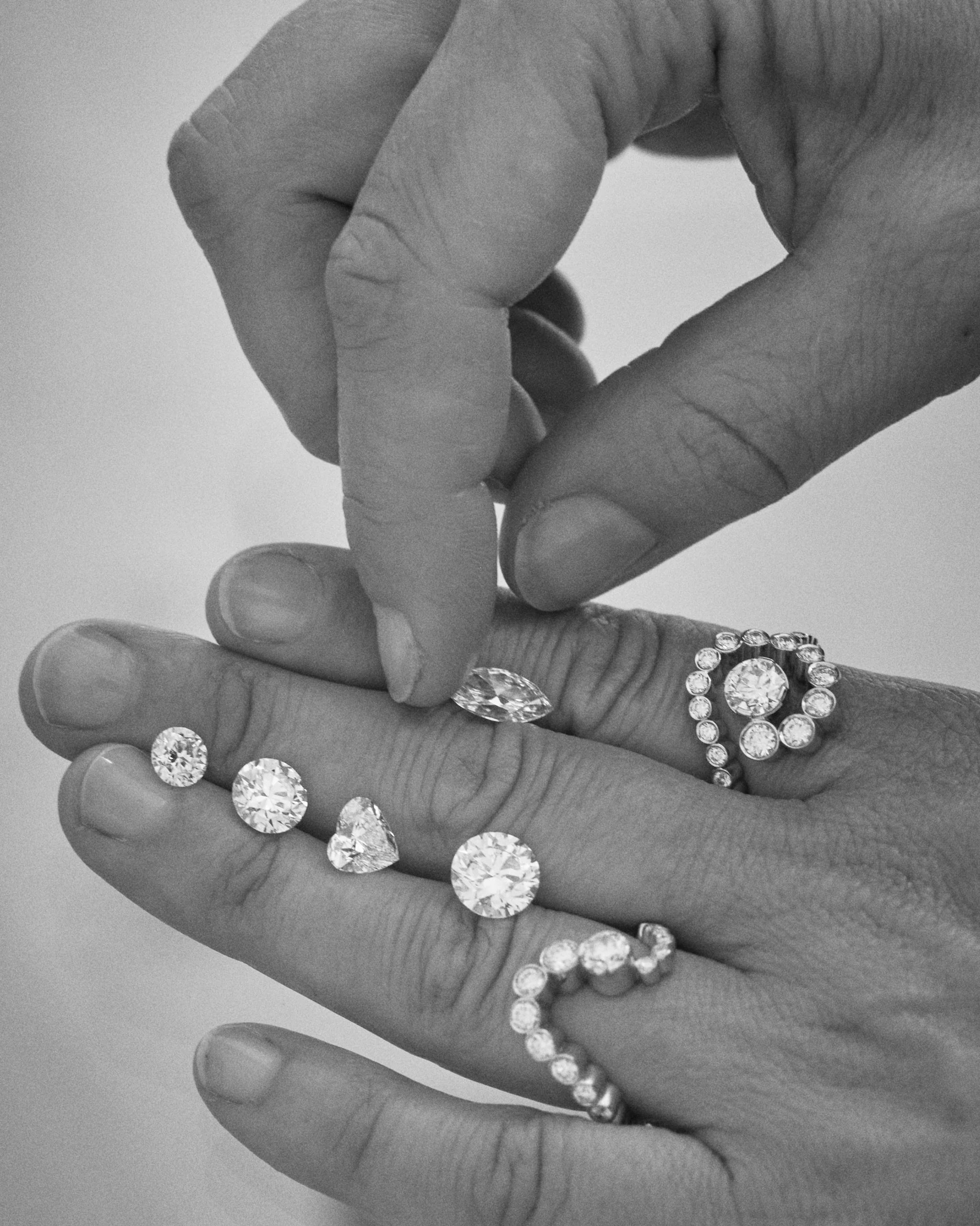 Loose diamonds on hands with rings.